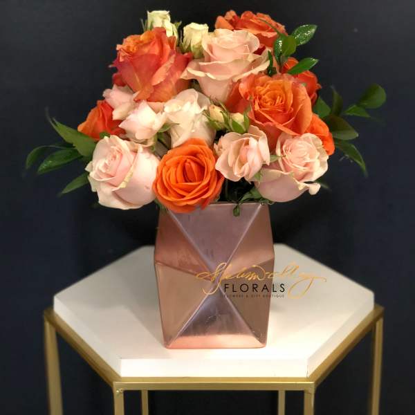 Bouquet of pink and orange roses in a geometric vase