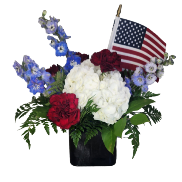 Red, white, and blue floral arrangement with an American flag in a black vase