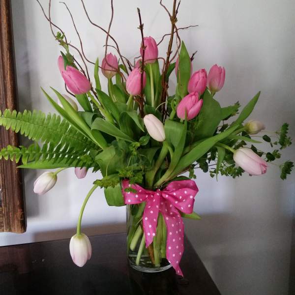 Pink and white tulips in a clear glass vase with a pink polka-dot bow