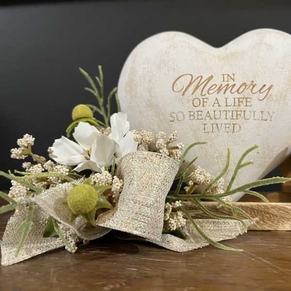 Heart-shaped memorial plaque with a small floral accent and ribbon