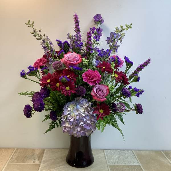 Mixed bouquet in a dark vase with pink roses and purple flowers
