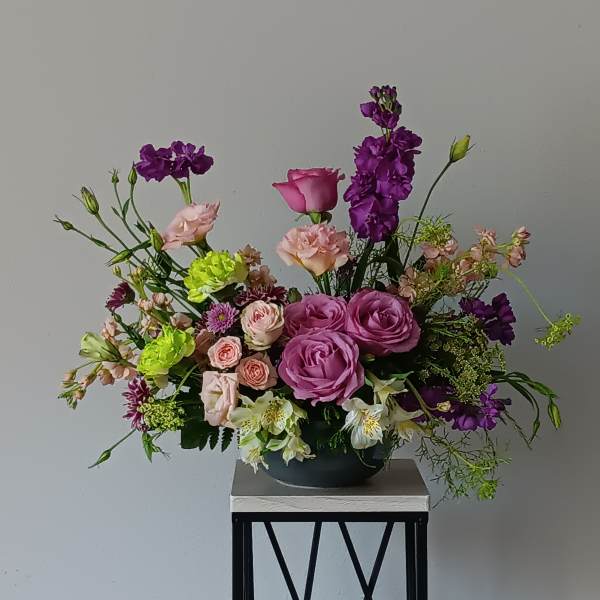 Mixed bouquet of pink and purple flowers in a low black bowl