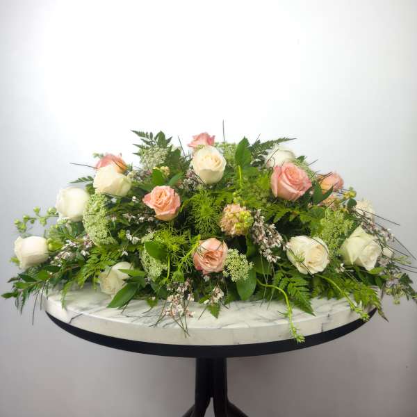 Low floral arrangement of white and peach roses on a round table