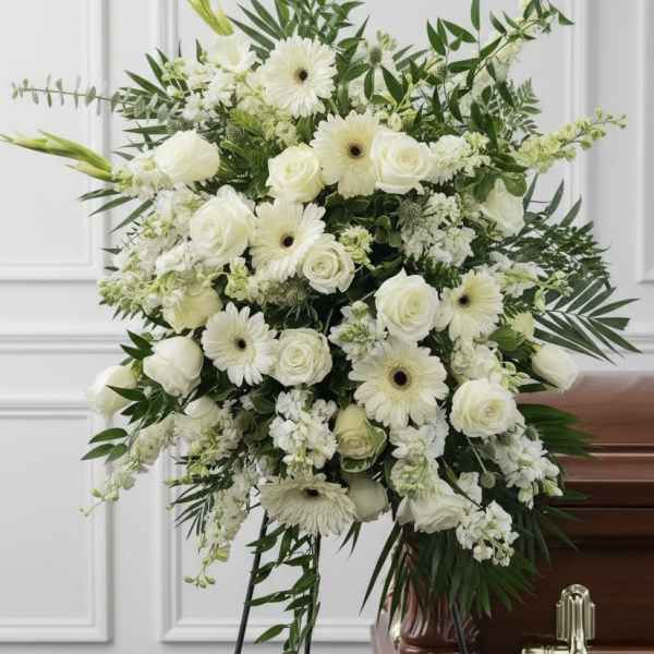 White floral funeral spray with roses and gerbera daisies on a stand