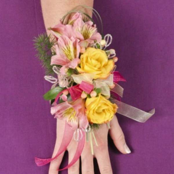 Pink and yellow floral wrist corsage on a hand