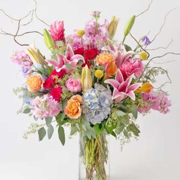 Mixed bouquet of pink, purple, and orange flowers in a clear glass vase