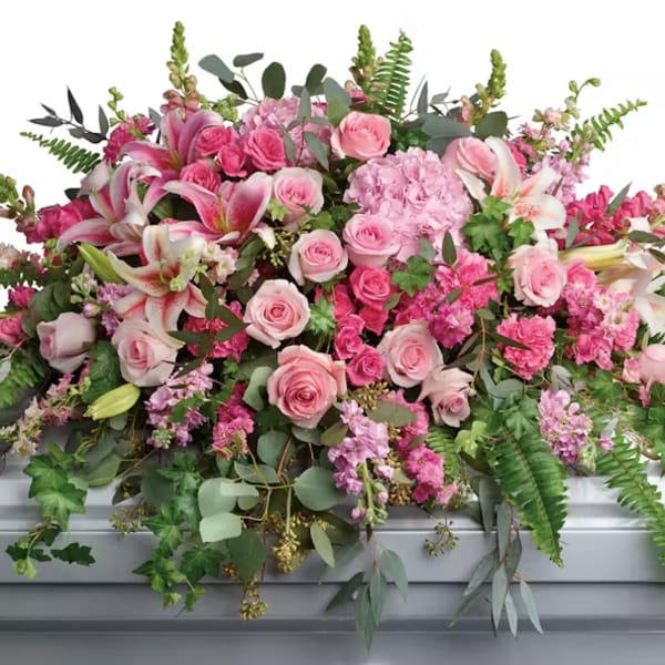 Large pink floral spray with roses and lilies on a casket