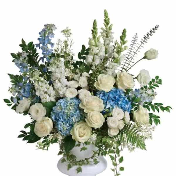 White and blue floral arrangement in a white pedestal vase