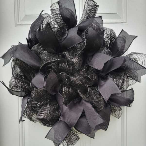 Black mesh wreath with gray ribbon loops on a white door
