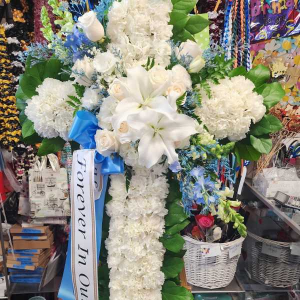 White floral standing cross with lilies and roses on an easel