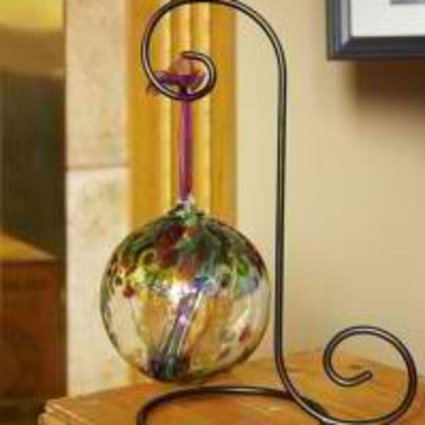 Decorative metal stand holding a colorful glass orb