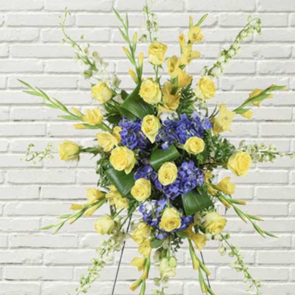 Yellow roses and purple flowers in a standing spray on an easel