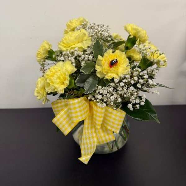 Yellow carnations in a round vase with a gingham bow