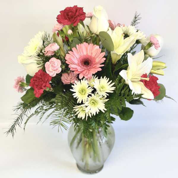 Mixed bouquet of pink, white, and red flowers in a glass vase