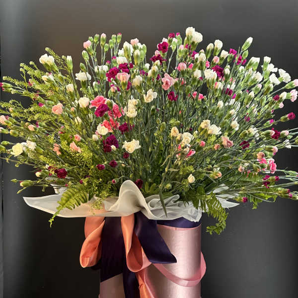 Large mixed bouquet of pink, white, and magenta carnations in a pink hatbox