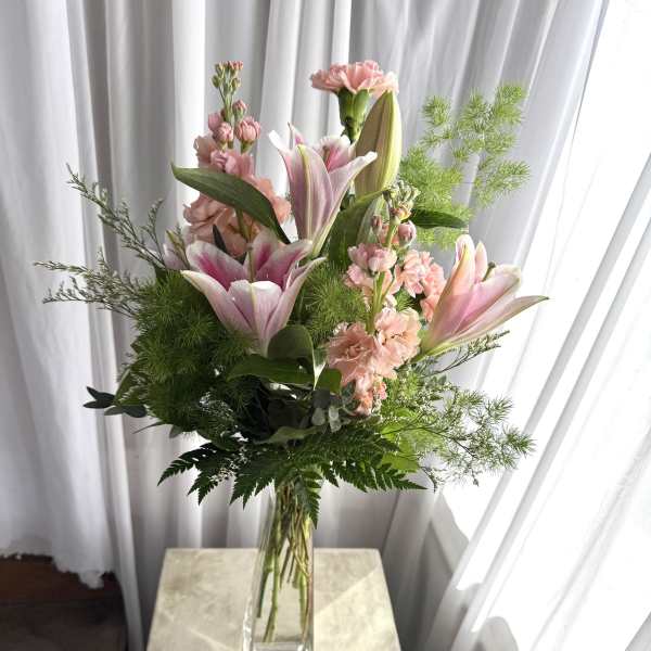 Pink lilies and carnations in a clear glass vase