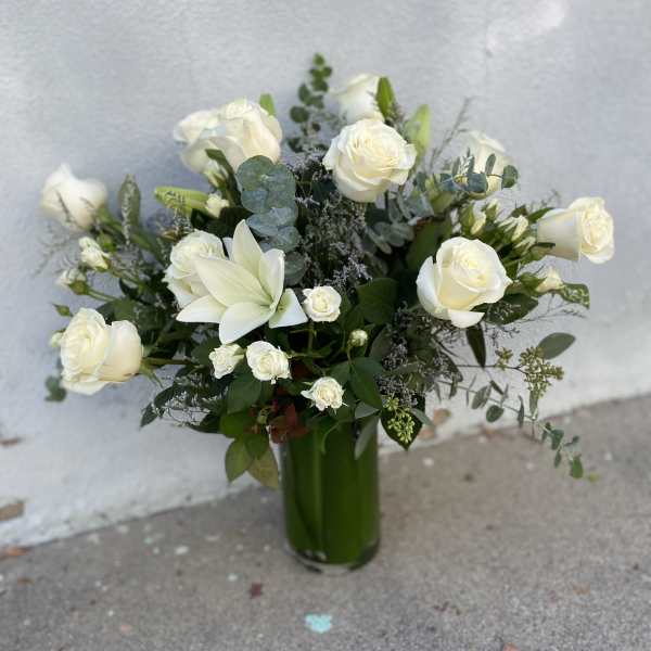 White roses and lilies arranged in a tall green vase