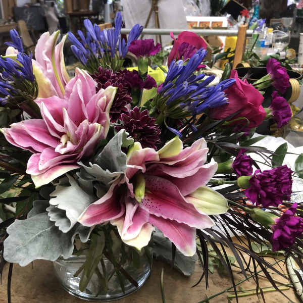 Pink lilies and purple flowers arranged in a glass vase