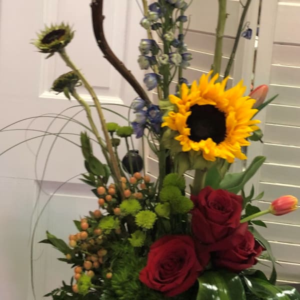 Tall mixed bouquet with sunflowers, red roses, and blue flowers