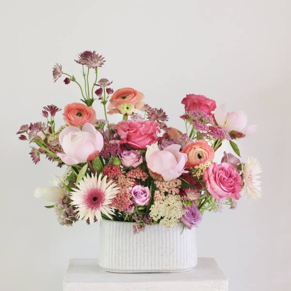 Pink and peach mixed flowers in a white ribbed vase