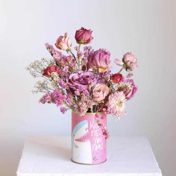 Pink and purple dried flower arrangement in a decorated tin can