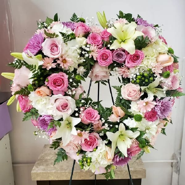 Heart-shaped floral wreath with pink and white flowers on an easel