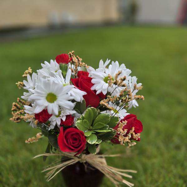 Bouquet of red roses and white daisies in a dark vase