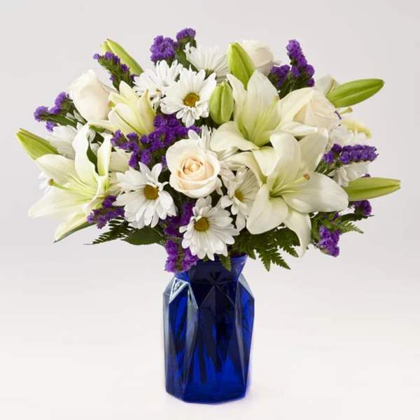 White lilies, daisies, and roses in a blue vase