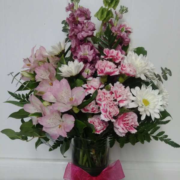 Pink and white mixed flower arrangement in a clear glass vase with a pink bow