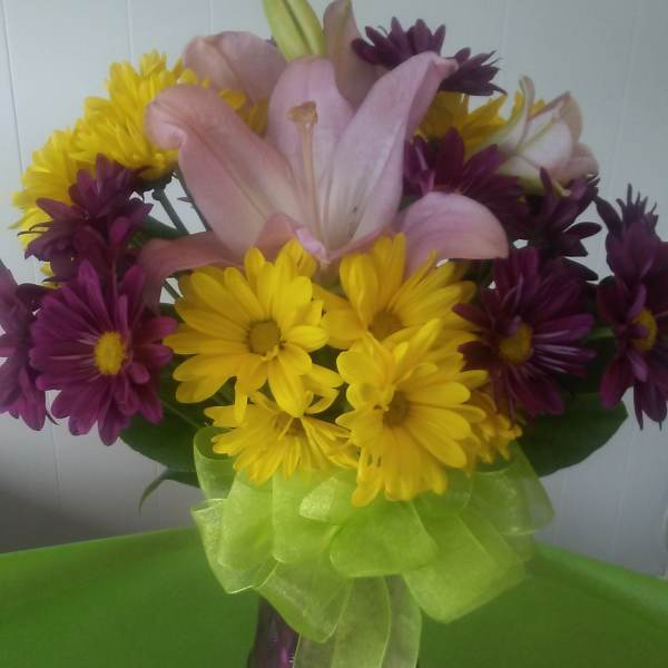 Bouquet of pink lilies and yellow and purple daisies in a vase