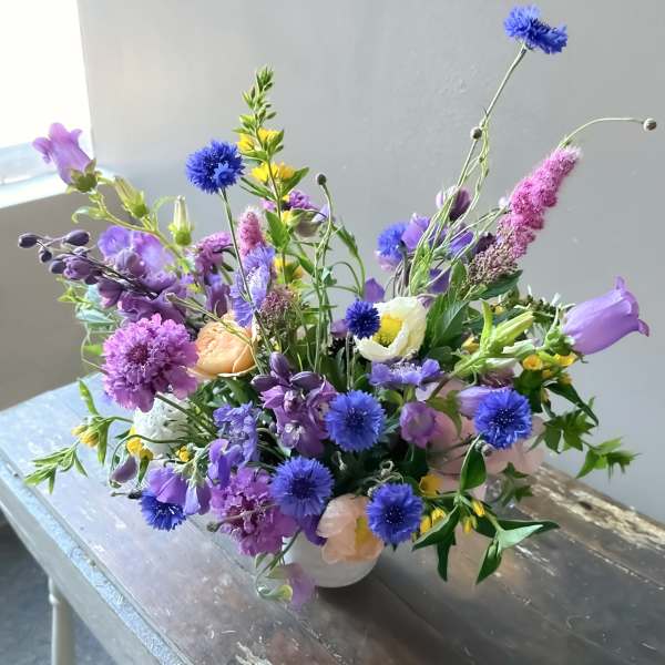 Mixed purple and blue bouquet in a white vase
