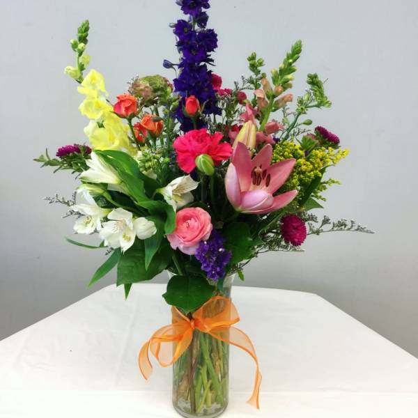 Colorful mixed bouquet in a glass vase with an orange ribbon
