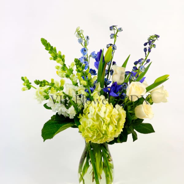 Blue, white, and yellow flowers arranged in a glass vase