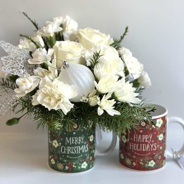 White floral arrangement in a Christmas mug with a silver ornament