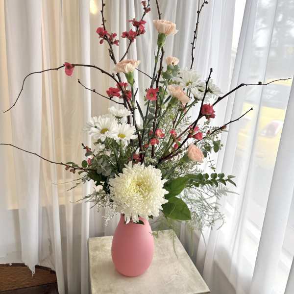 Tall floral arrangement in a pink vase with white and pink blooms
