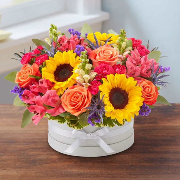Bright mixed bouquet in a white round box with a ribbon