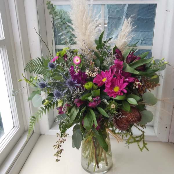 Mixed bouquet in a clear glass vase with pink and purple blooms