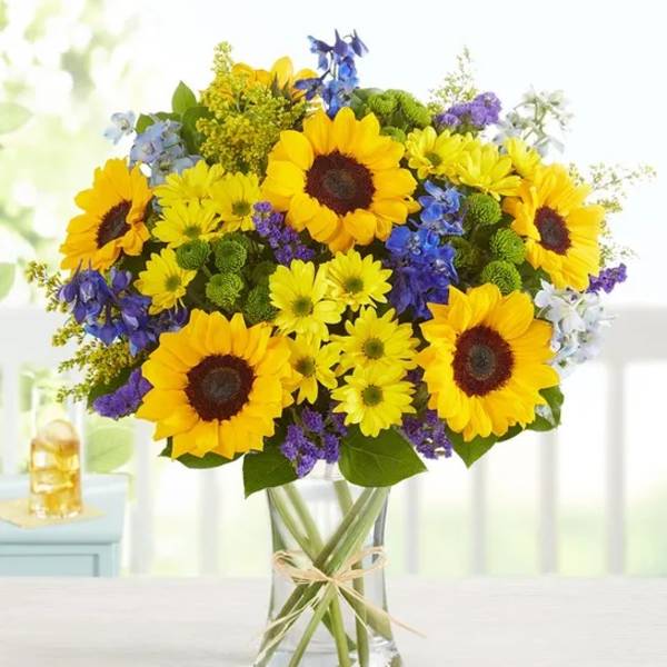 Bouquet of yellow sunflowers and purple flowers in a clear glass vase