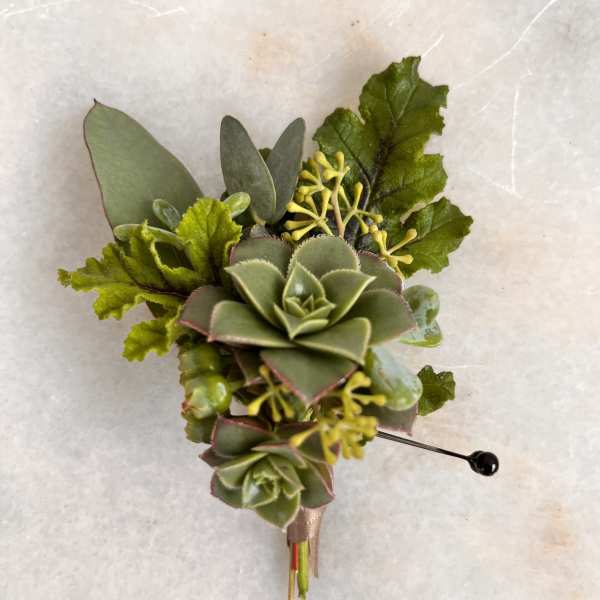 Succulent boutonniere with green foliage and yellow accents