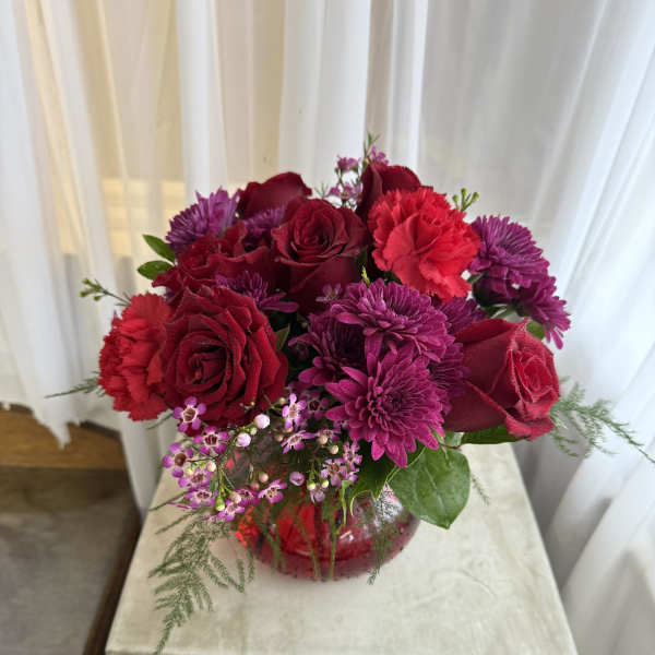 Bouquet of red roses and purple mums in a red vase