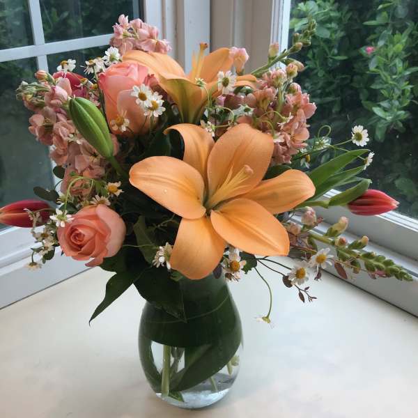 Peach lilies and roses in a glass vase