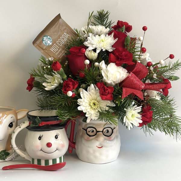Holiday floral arrangement in a Santa mug with red and white flowers
