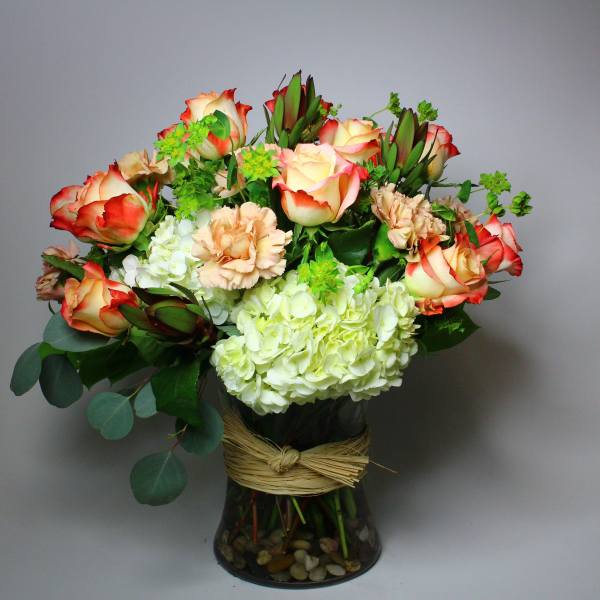 Bouquet of red-edged roses and pale hydrangeas in a glass vase