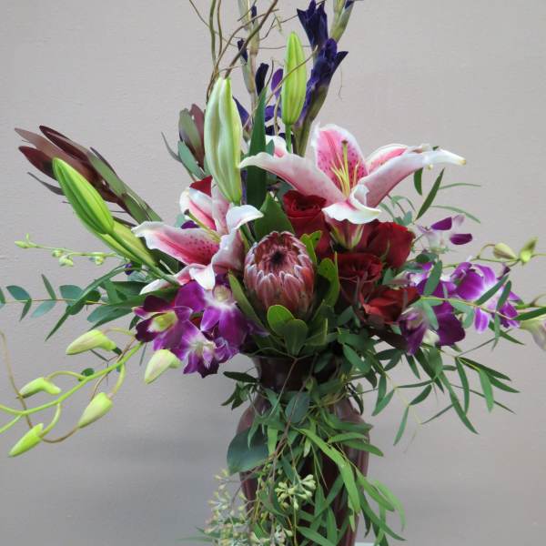 Tall bouquet of lilies, roses, and orchids in a vase