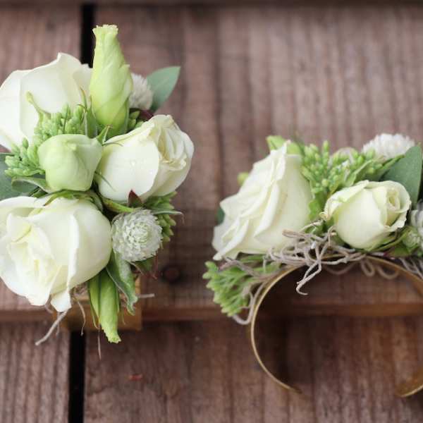 White rose wrist corsage with green accents on a band
