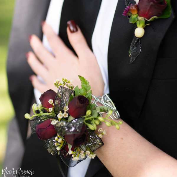 Boutonniere and wrist corsage with dark red roses and white accents