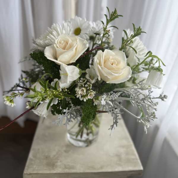 White roses and daisies in a clear glass vase