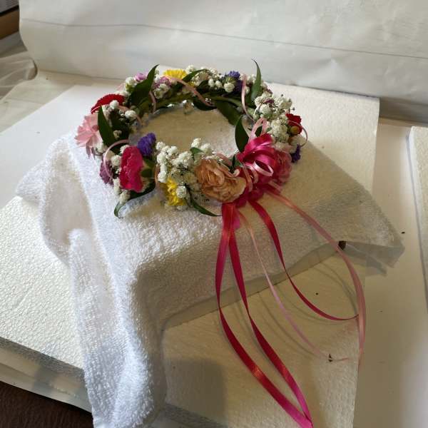 Floral crown with pink, yellow, purple, and white flowers and ribbon streamers