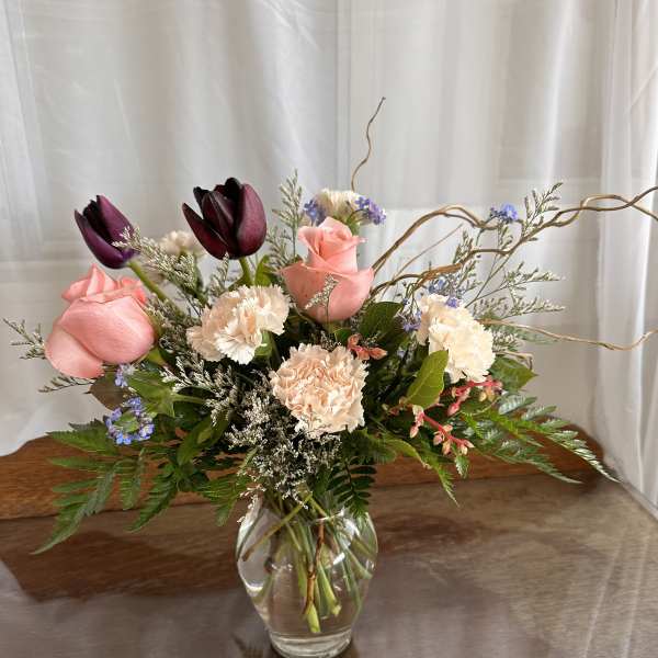 Pink roses and dark tulips in a clear glass vase