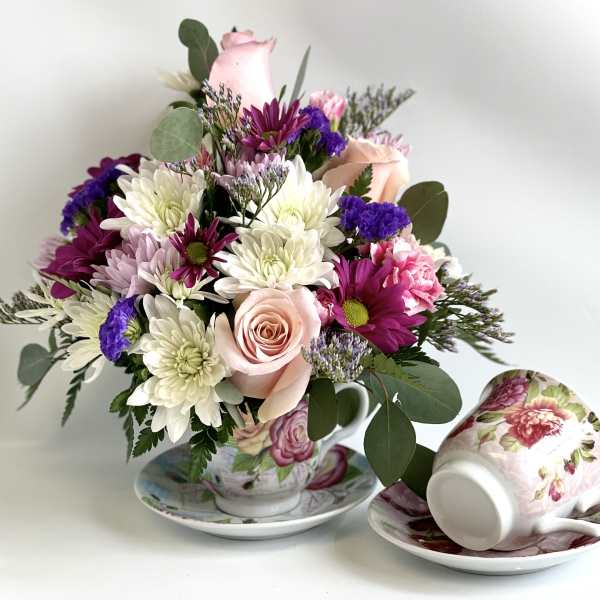Bouquet of pink, white, and purple flowers in a floral teacup and saucer